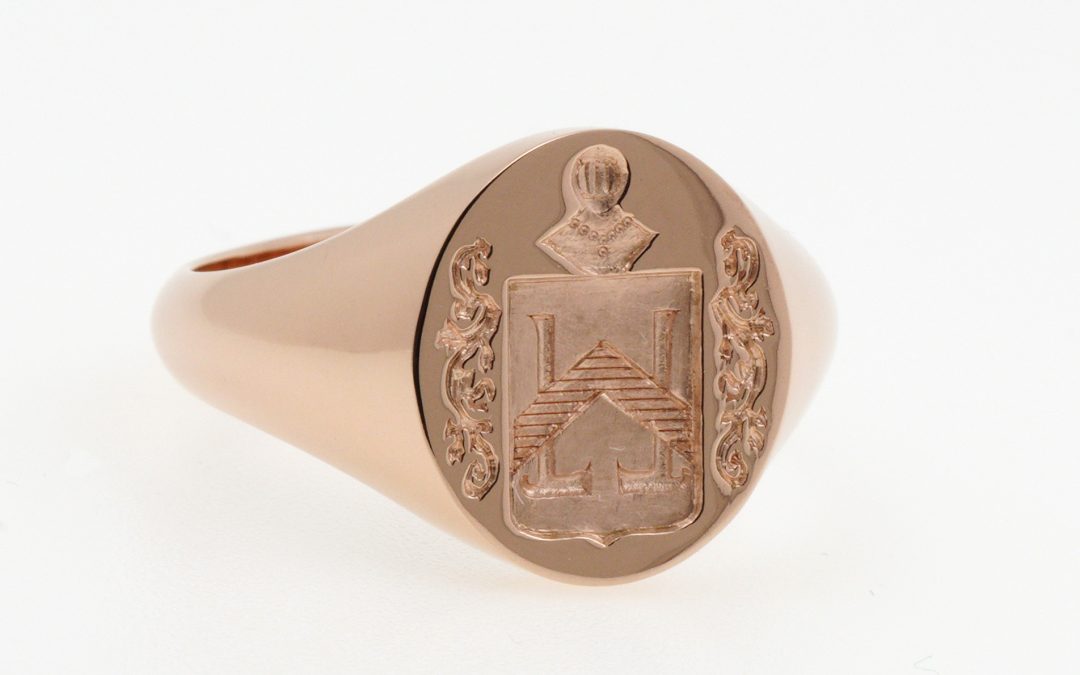 Rose gold signet ring with a cushion-shaped shield, mantling and helmet