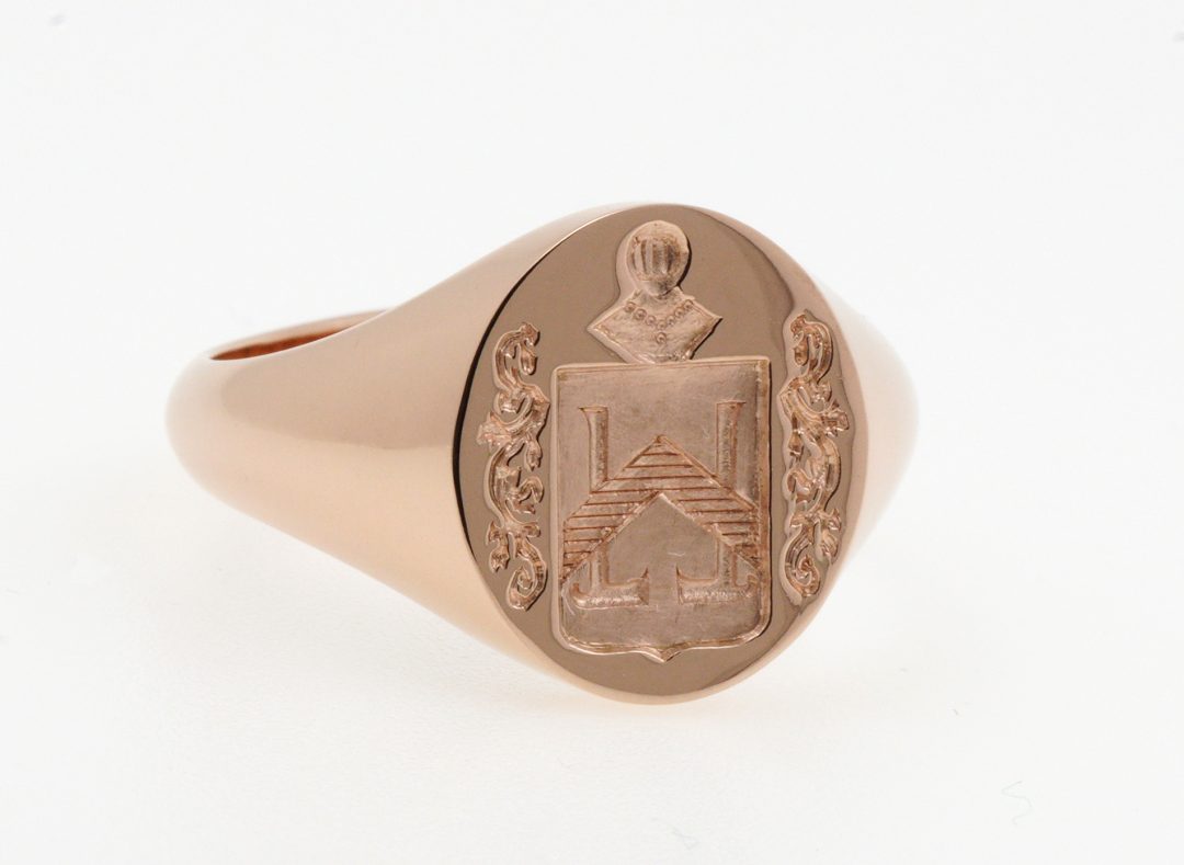 Chevalière armoriée en or rose avec gravure héraldique complète comprenant un écu, un casque de chevalier et des lambrequins stylisés, création sur mesure Bijouterie Griffon.