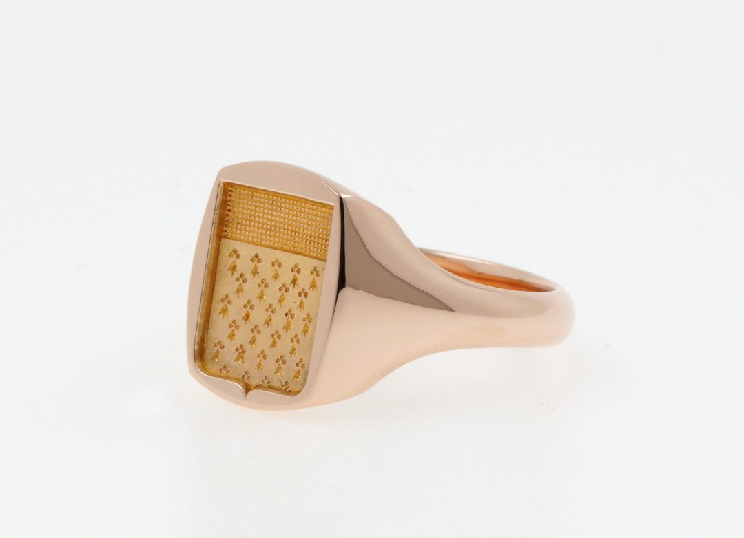 Chevalière armoriée en or rose avec gravure héraldique personnalisée sur le plateau, écu sculpté avec détails de blason, création artisanale Bijouterie Griffon.