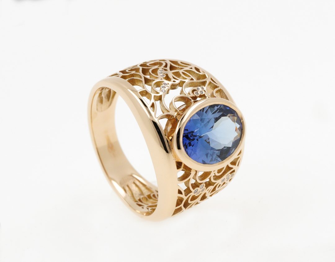 Bague bandeau en or jaune avec saphir bleu et monture ciselée ajourée.