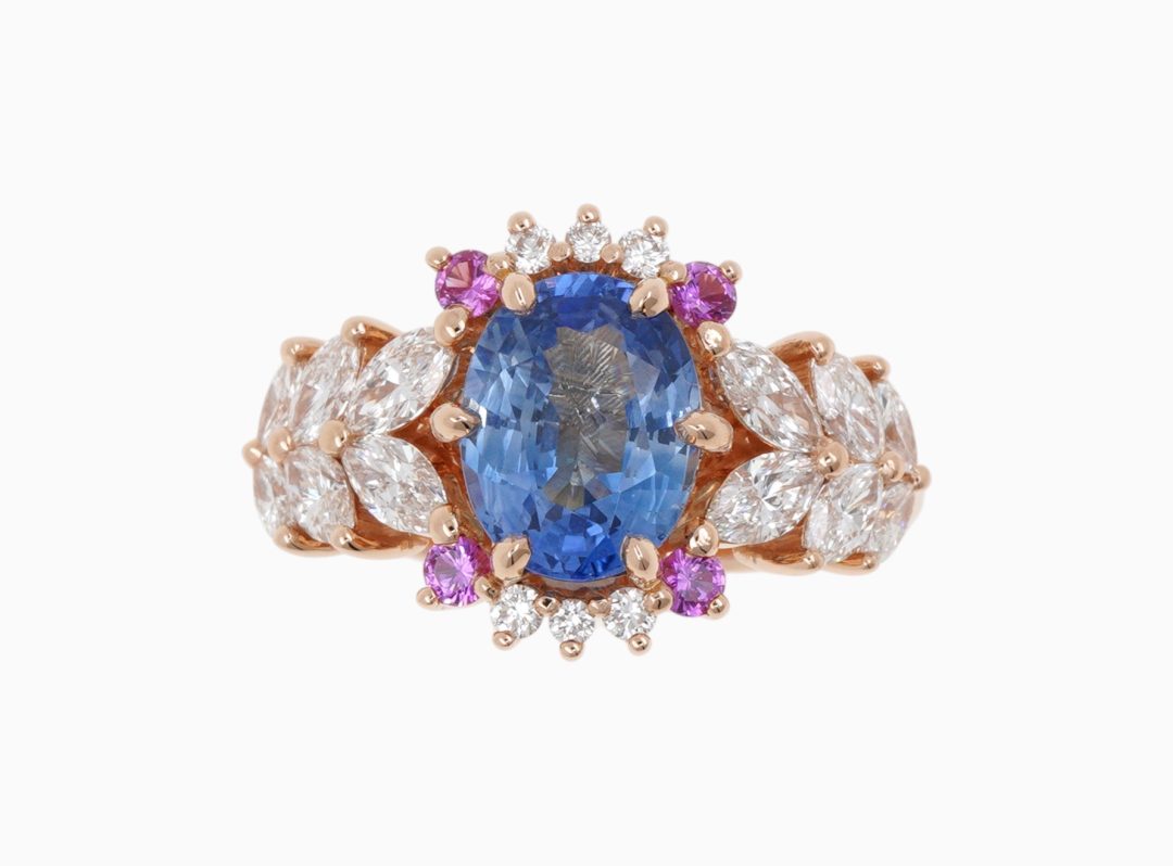 Bague de fiançailles en or rose sertie d'un saphir bleu et entourage de saphirs roses.