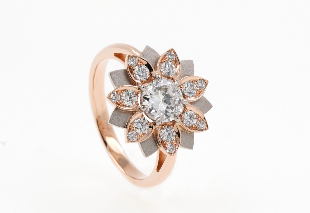 Bague en or rose brossé sertie d'un diamant et motif fleur de lys.