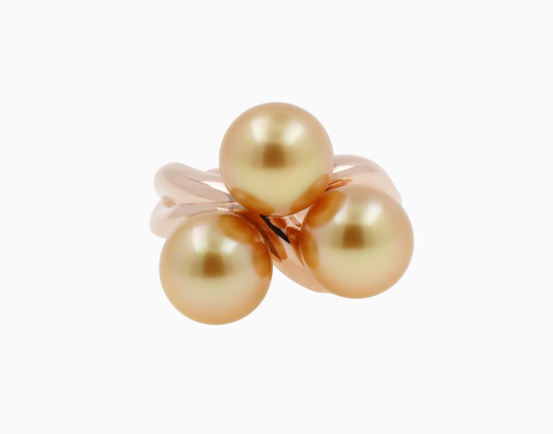 Bague torsadée en or rose sertie d'un trio de perles de culture aux reflets dorés.
