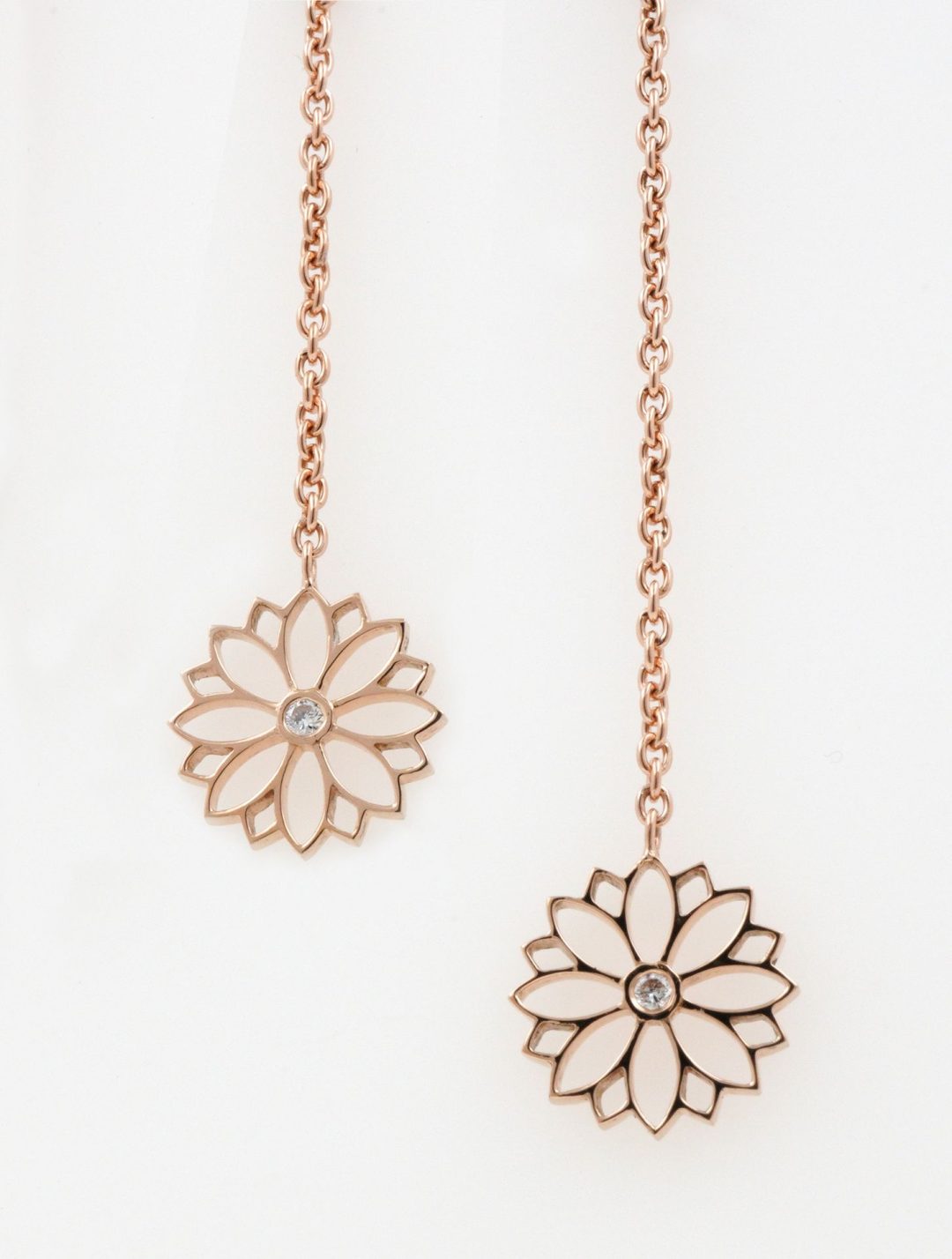 Boucles d'oreilles pendantes en or rose avec motif fleur de lys serti de diamants.