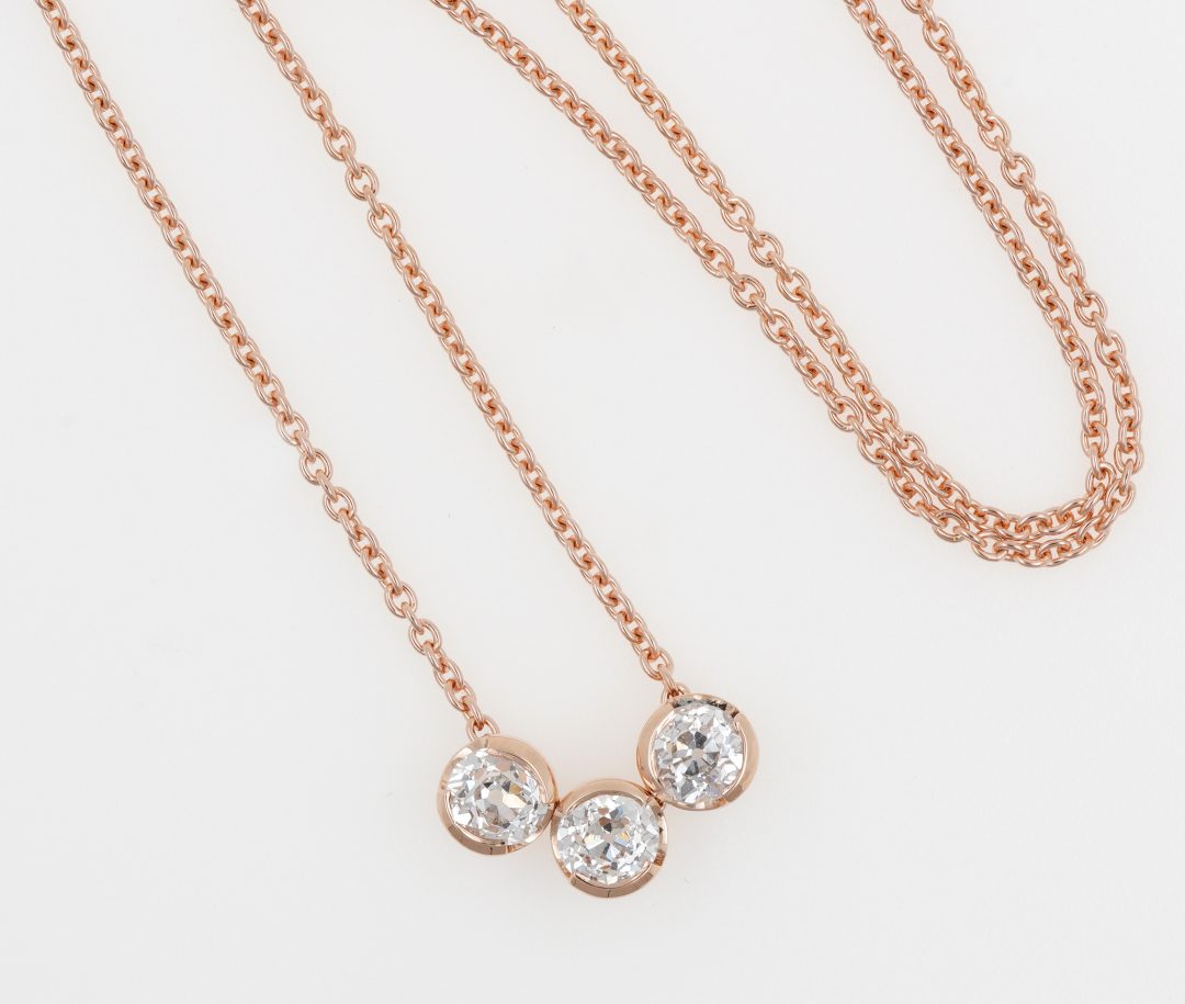 Collier en or rose avec un trio de diamants sertis demi-clos.