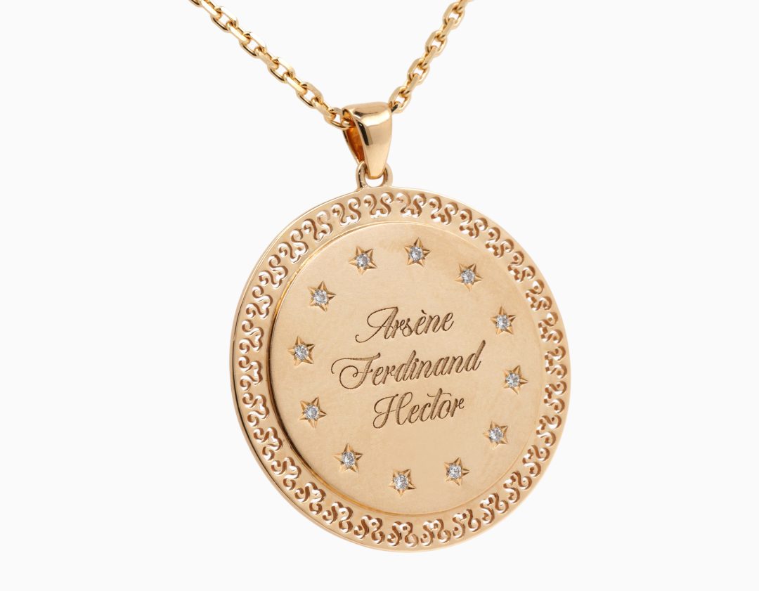 Pendentif médaille en or jaune serti de diamants avec gravure personnalisée.