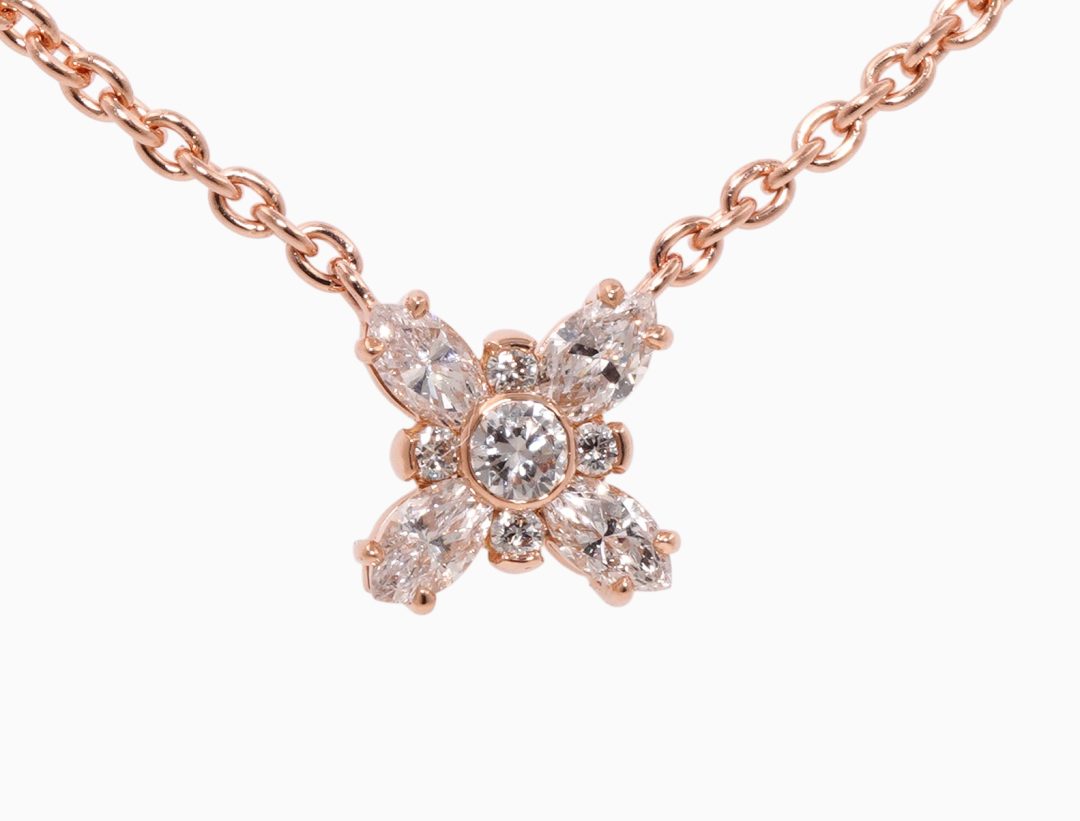 Pendentif en or rose en forme de trèfle serti de diamants.